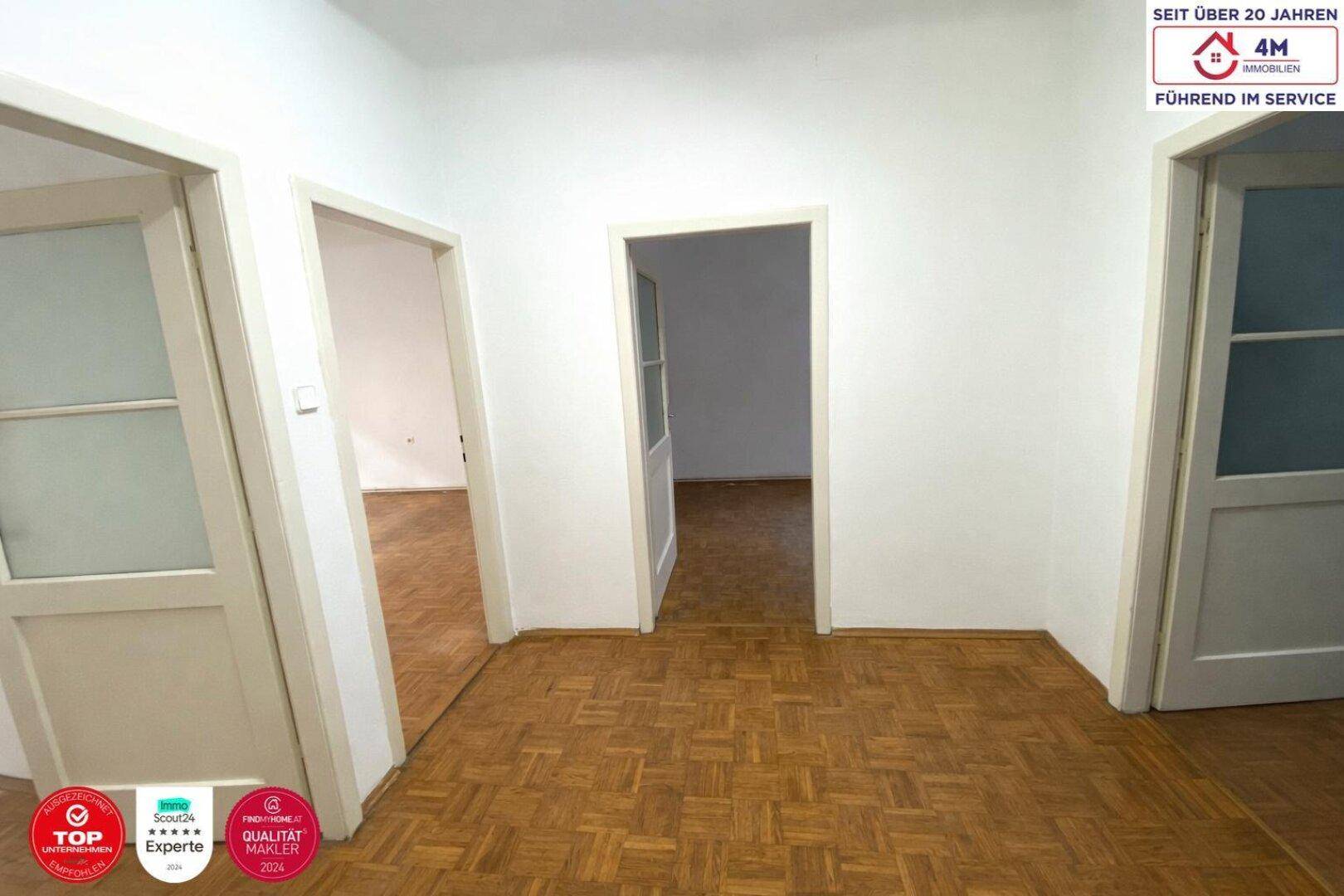 Heller Flur mit Fischgrätparkett und Zugang zu mehreren Zimmern.