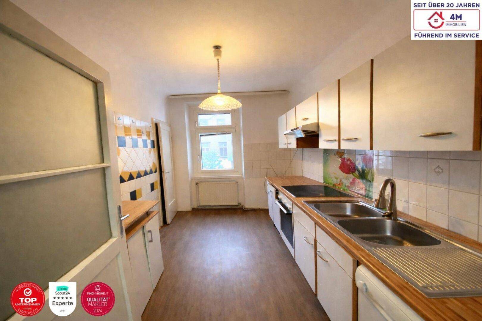 Funktionale Einbauküche mit Fenster, Spüle und Herd, bereit zur Modernisierung.