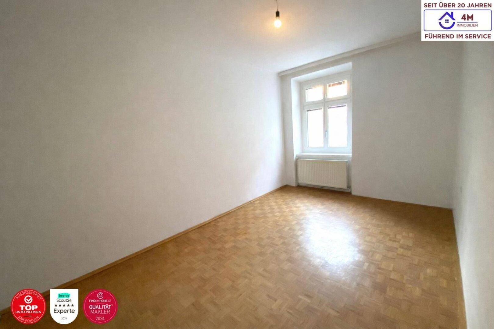 Lichtdurchflutetes Zimmer mit Holzparkettboden und einem großen Fenster.