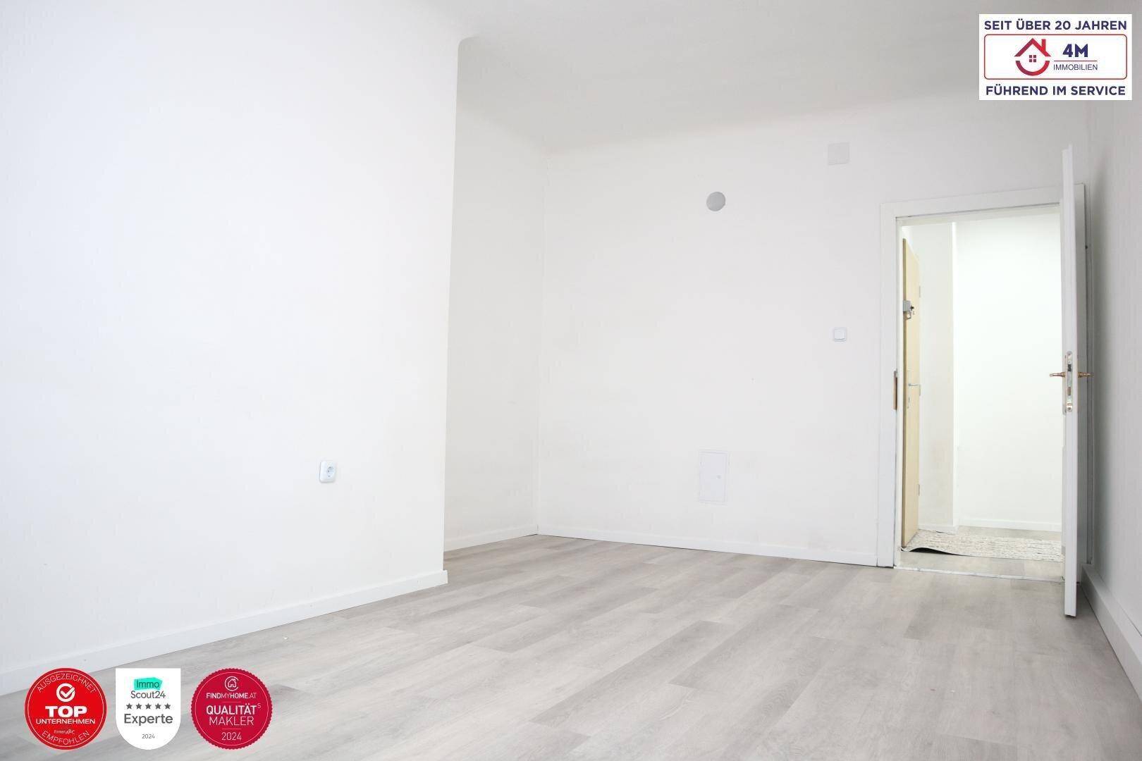 Geräumiges Schlafzimmer mit weiß gestrichenen Wänden und hellem Laminatboden.
