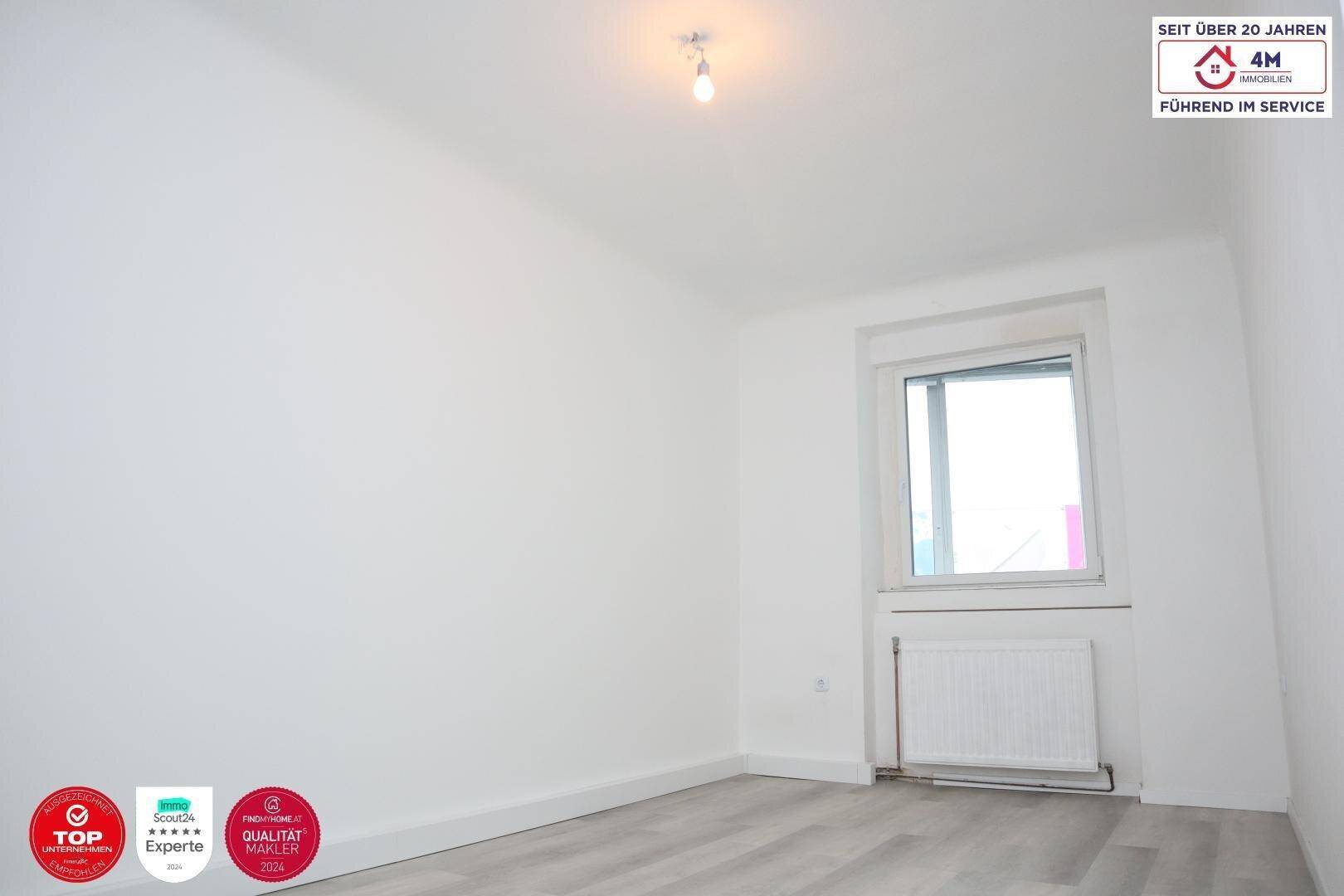 Helles Schlafzimmer mit Laminatboden und Fenster, bereit zur individuellen Gestaltung.