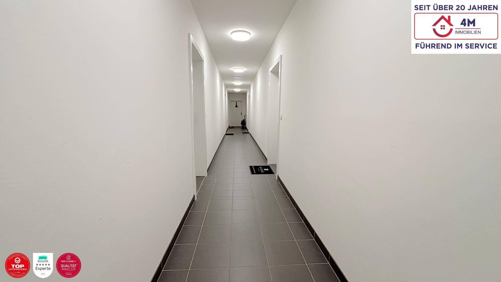 Langer, heller Flur mit mehreren Türen und Fliesenboden, der zu den verschiedenen Räumen führt.