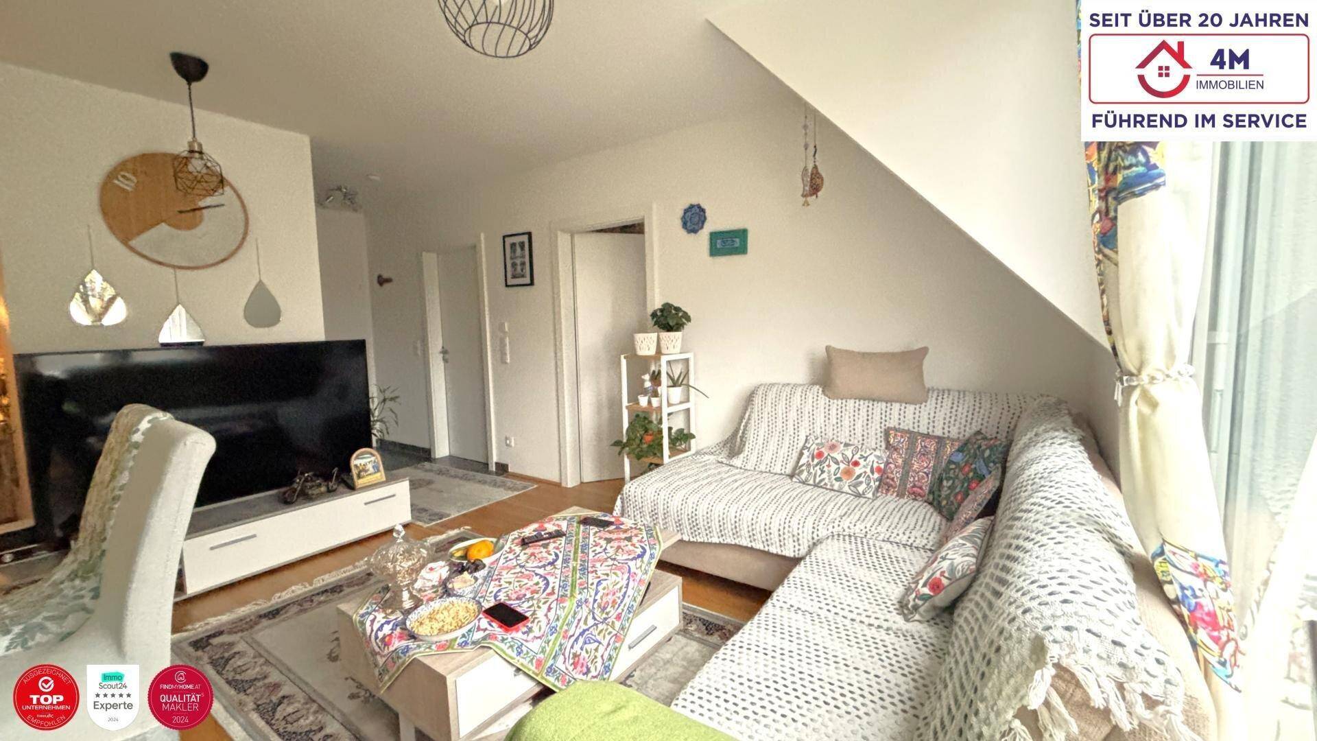 Gemütliches Wohnzimmer mit Dachschräge, bequemer Eckcouch und Fernseher, perfekt zum Entspannen.