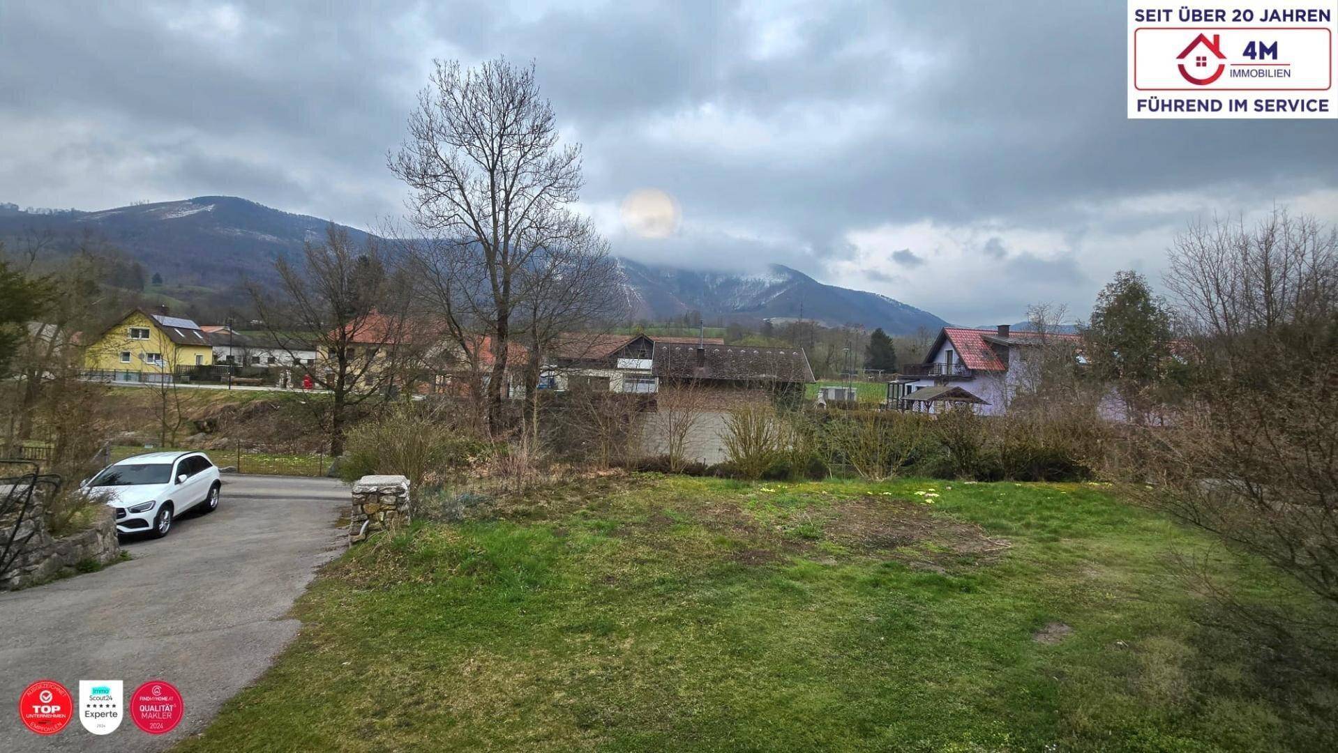 Weitläufiger Blick auf die umliegende Landschaft mit Bergen und ländlicher Bebauung unter bewölktem Himmel.
