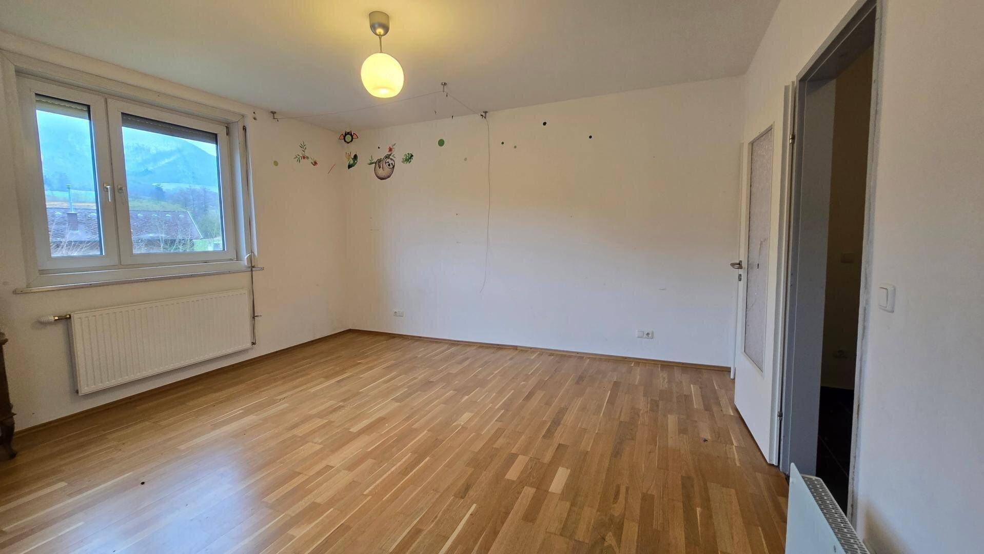 Geräumiges Zimmer mit Holzparkettboden und Fenster, bietet vielseitige Nutzungsmöglichkeiten.