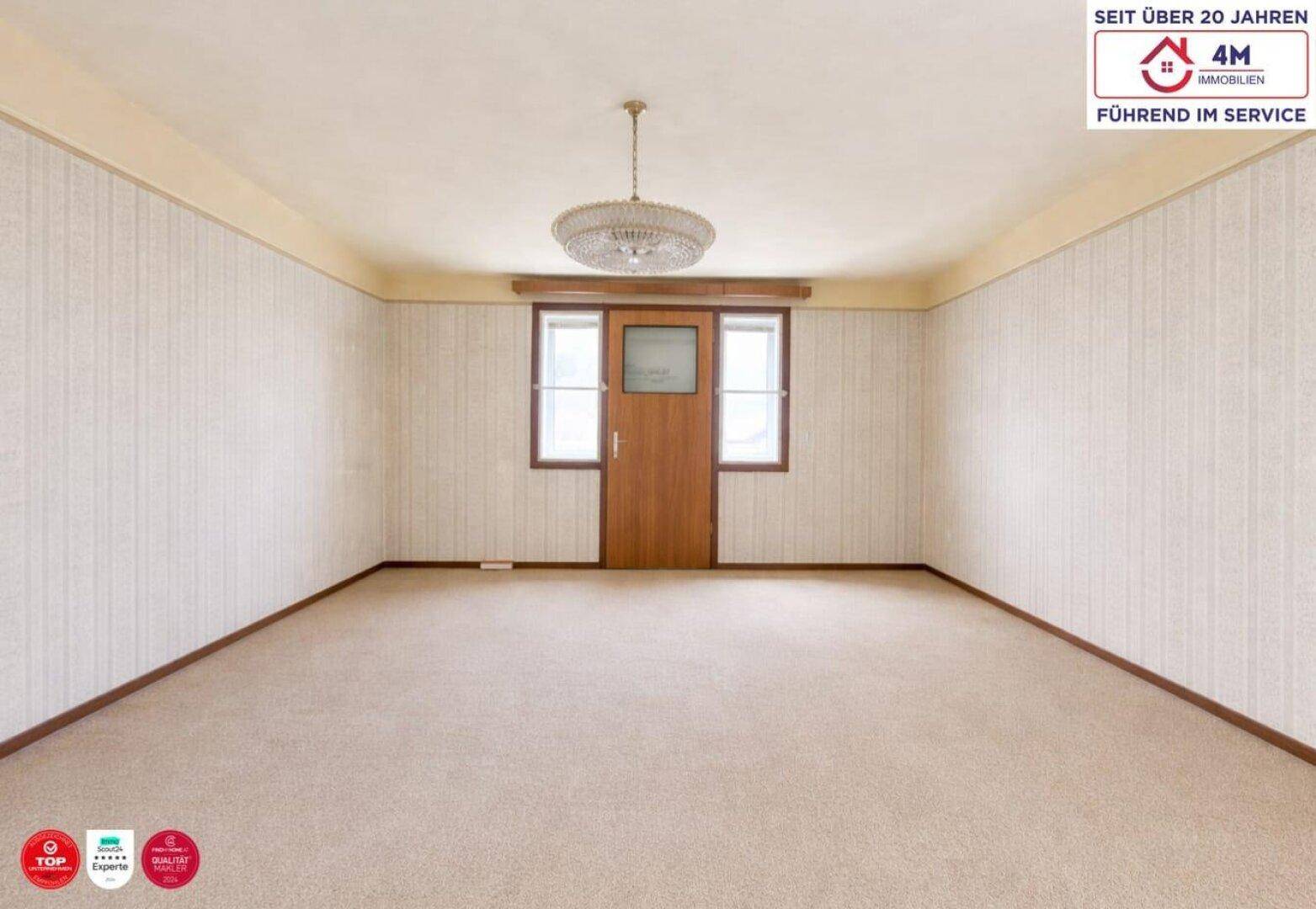 Geräumiges Zimmer mit Teppichboden, strukturierten Tapeten und einem Kronleuchter.