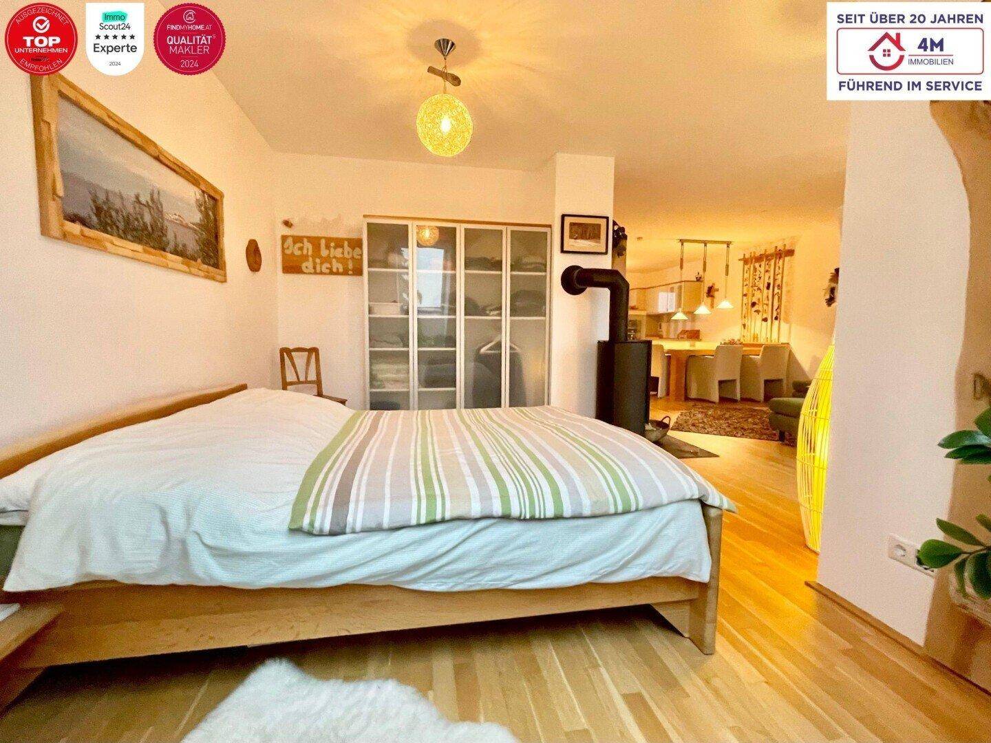 Helles Schlafzimmer mit Holzbett und Kaminofen, der eine behagliche Atmosphäre im Raum schafft.
