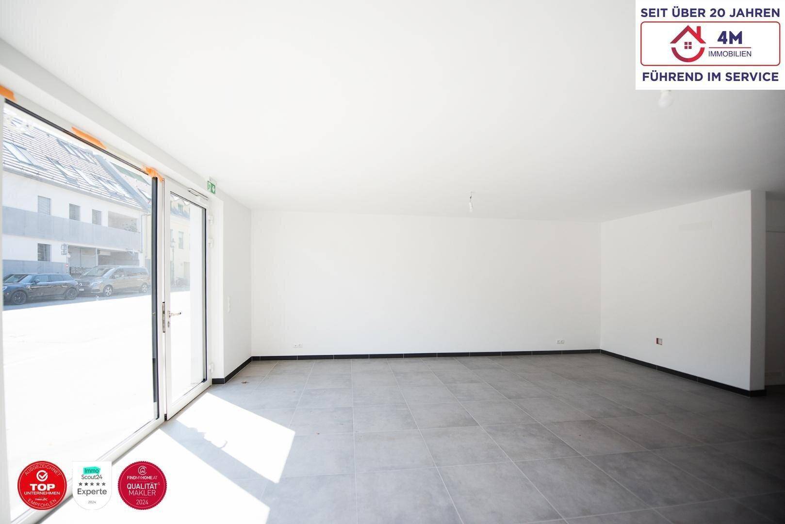 Großer, heller Raum mit Zugang nach draußen durch eine breite Glasfront, ideal für gewerbliche Nutzung.