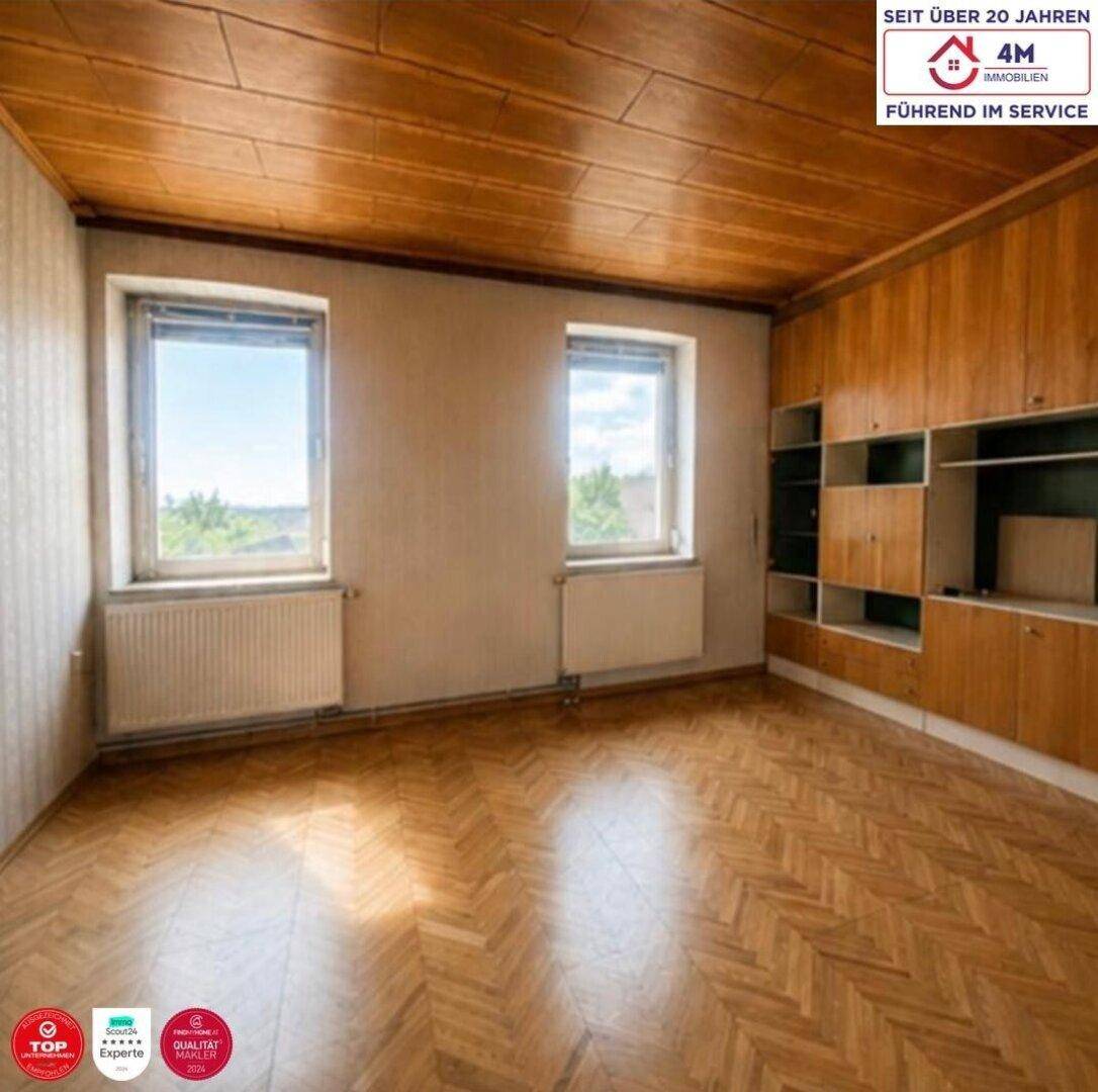 Helles Schlafzimmer mit Fischgrätparkett, Holzdecke und integrierten Holzschränken.