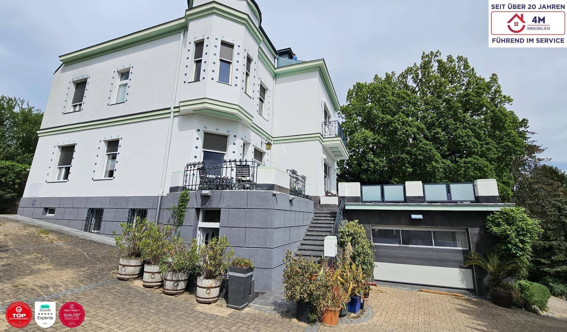 Elegante weiße Villa mit grünen Akzenten und einer integrierten Garage.