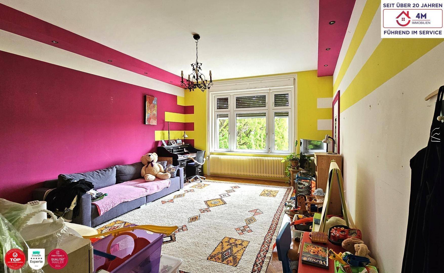 Schlafzimmer oder Mehrzweckraum mit farbigen Streifenwänden, Sofa, Schreibtisch und Fenster mit Rollläden.