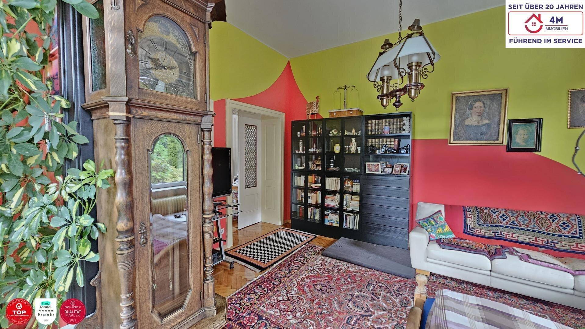 Gemütliche Wohnzimmerecke mit Standuhr, farbigen Wänden, Bücherregal und Sofa.