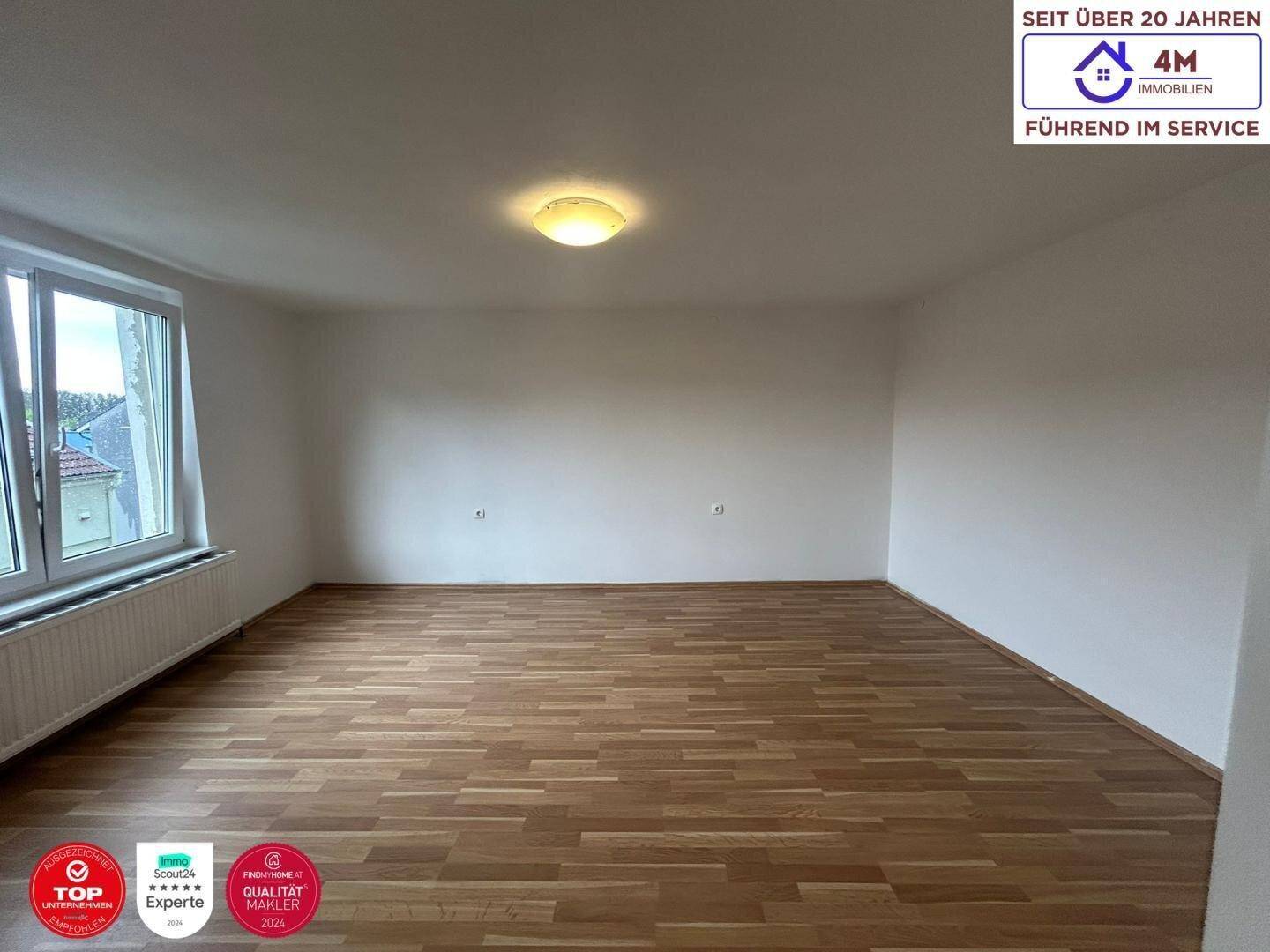 Heller Raum mit Parkettboden und großem Fenster, bietet vielseitige Nutzungsmöglichkeiten.