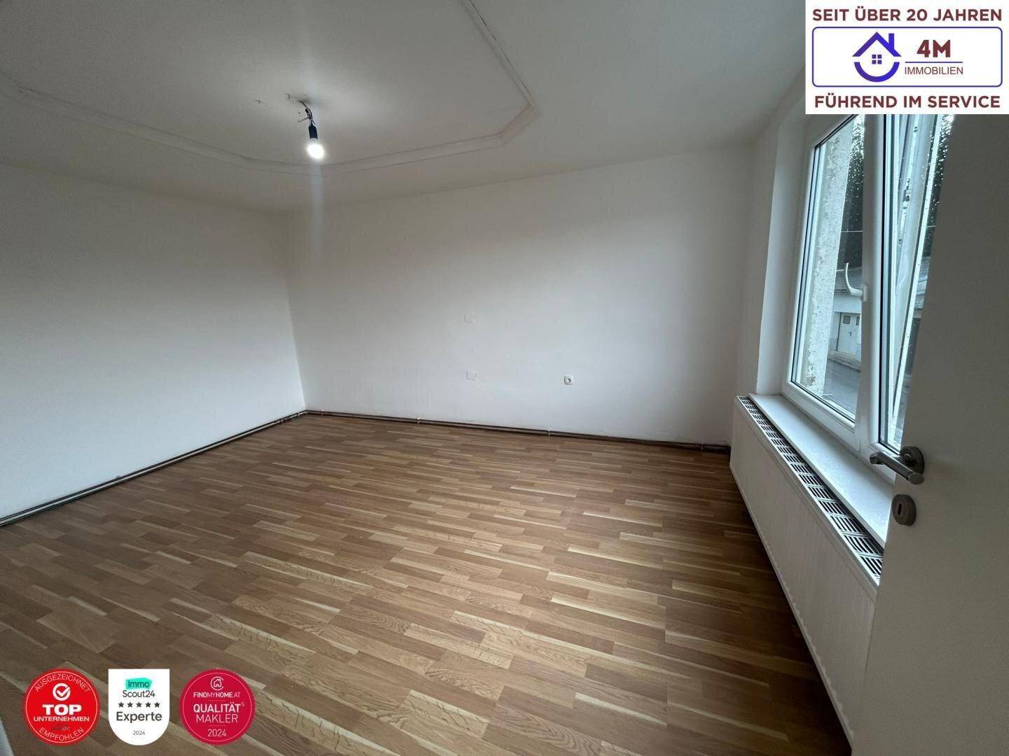 Geräumiges Zimmer mit Parkettboden und großem Fenster, ideal als Schlaf- oder Arbeitszimmer.