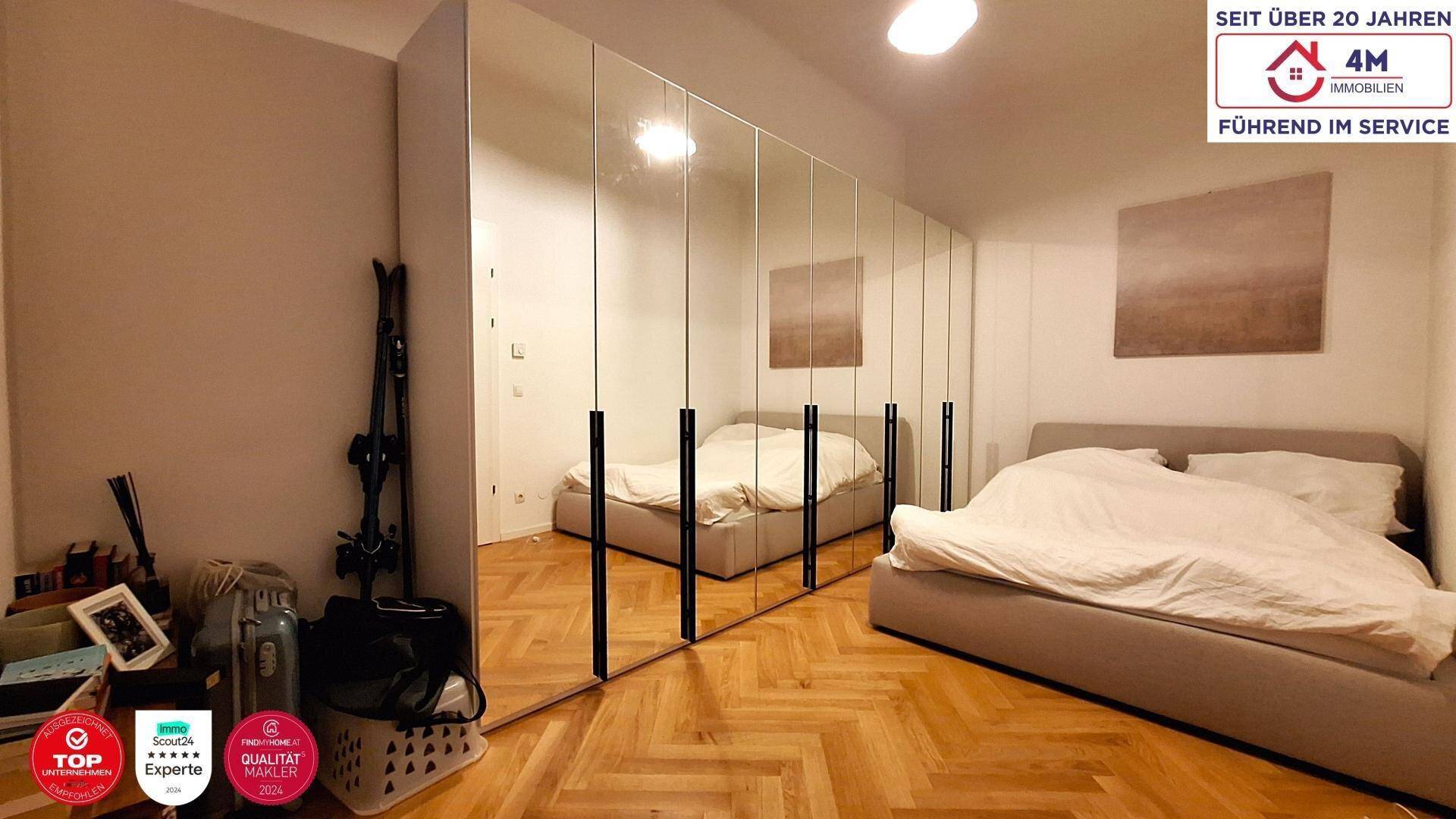 Schlafzimmer mit großem Bett und Spiegelschränken, Parkettboden und heller Atmosphäre.