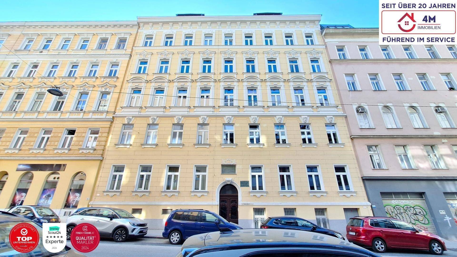 Klassische Fassade eines historischen Mehrfamilienhauses in einer belebten Stadtumgebung.