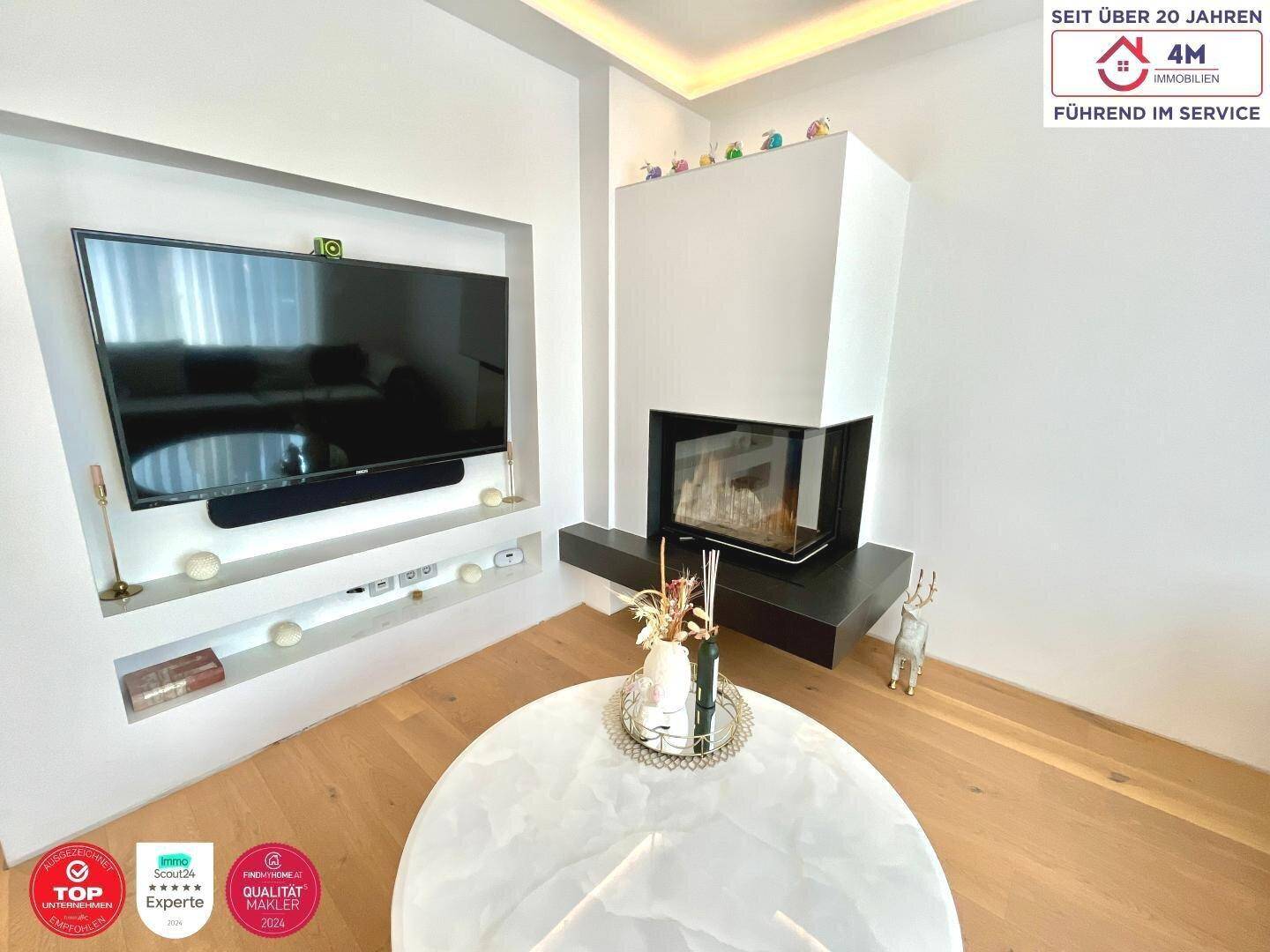Moderner Kaminbereich mit integriertem Fernseher und stilvollem Couchtisch im Wohnzimmer.
