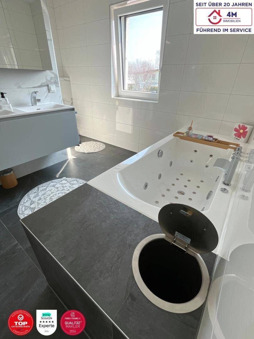 Whirlpool-Badewanne im modernen Badezimmer mit praktischem integriertem Abfalleimer.