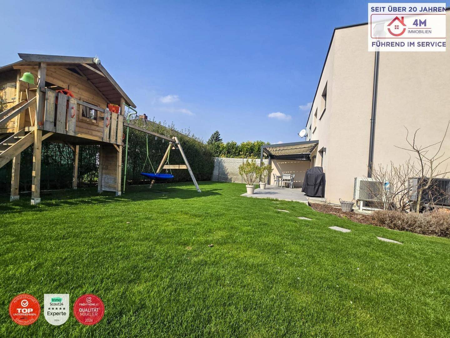 Großer Garten mit Rasenfläche, Kinderspielplatz und angrenzender Terrasse.