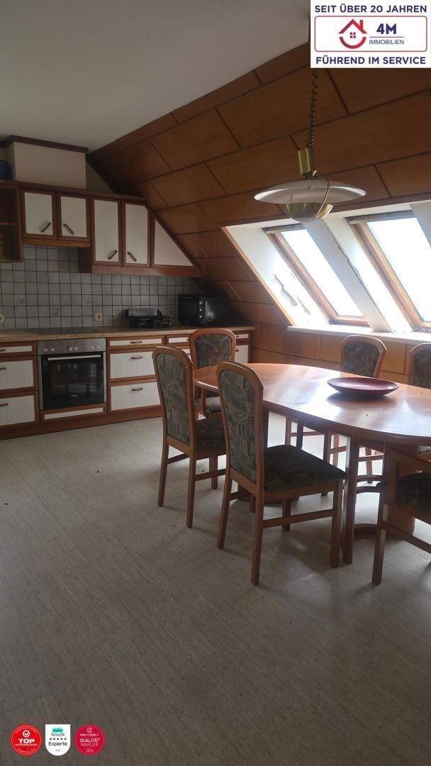 Geräumige Wohnküche mit Essbereich, Holzvertäfelung und Dachfenstern für viel Tageslicht.