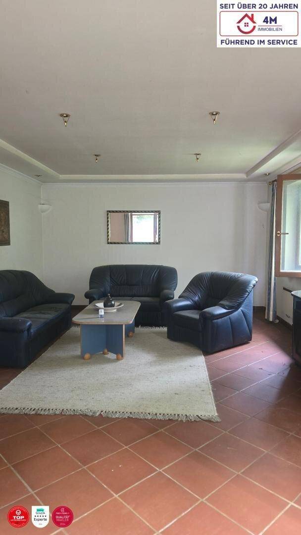 Helles Wohnzimmer mit bequemen Ledersofas, Teppich und Terrakottafliesen, ideal zum Entspannen.