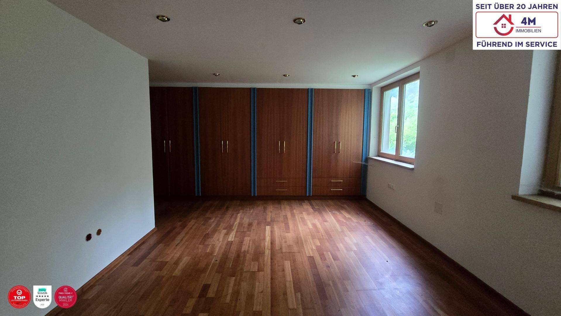 Helles Schlafzimmer mit Holzdielenboden und praktischen Einbauschränken entlang der Wand.