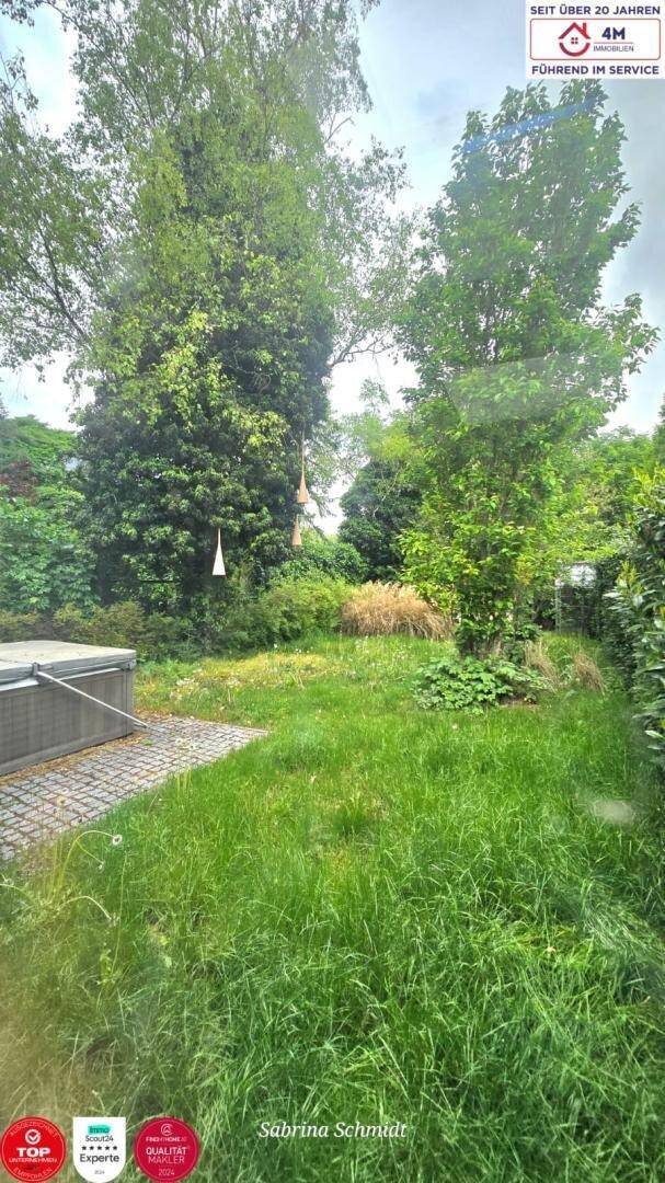 Grüner Gartenbereich mit Rasenfläche, Bäumen und einem Whirlpool.