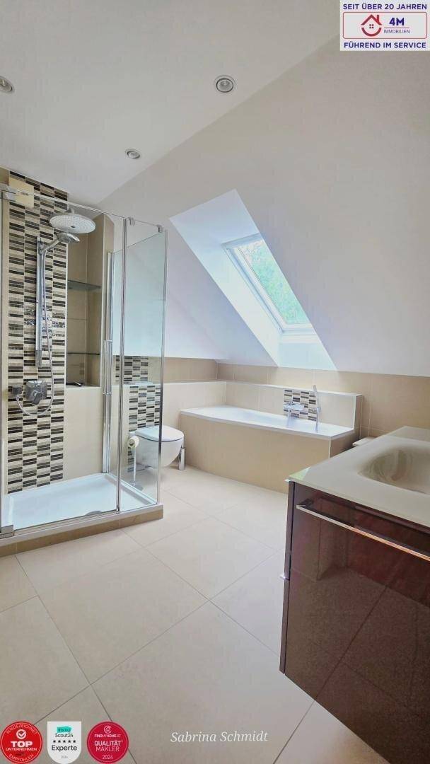 Modernes Dachgeschoss-Badezimmer mit Dusche, Badewanne, Dachfenster und hellen Fliesen.