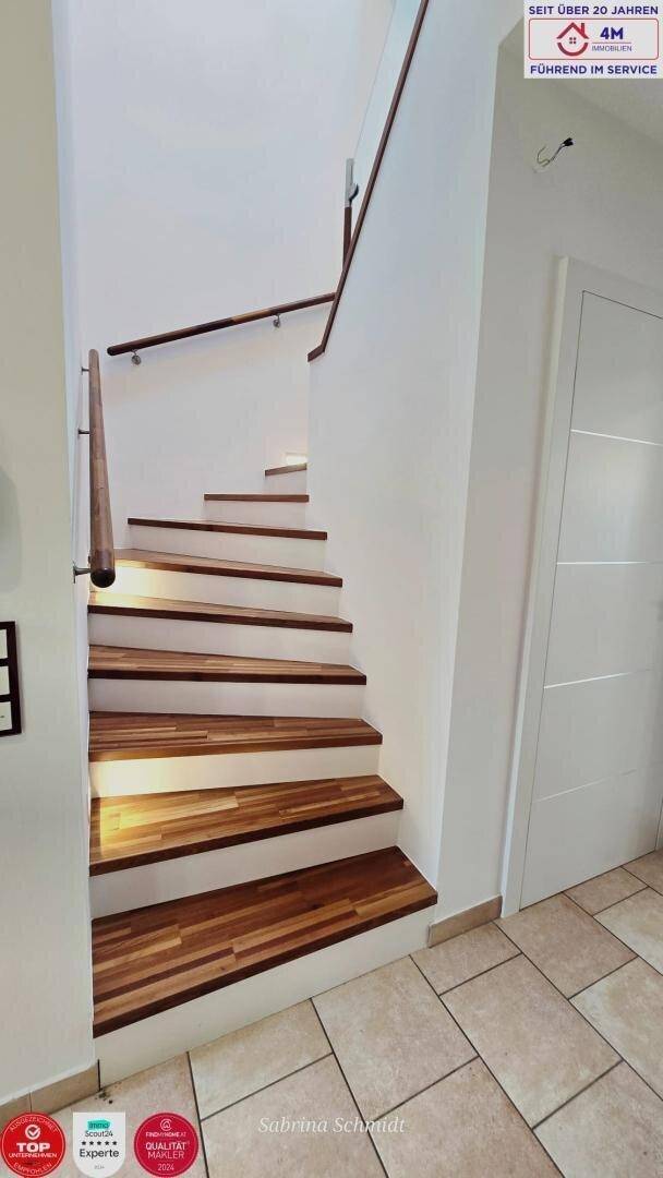 Elegante Holztreppe mit weiß gestrichenen Stufen und hellem Fliesenboden.