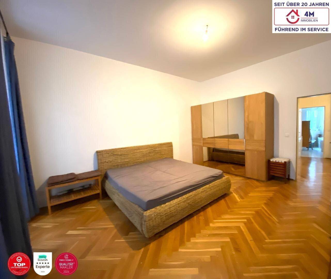 Geräumiges Schlafzimmer mit Fischgrätparkett, Doppelbett und großem Kleiderschrank.