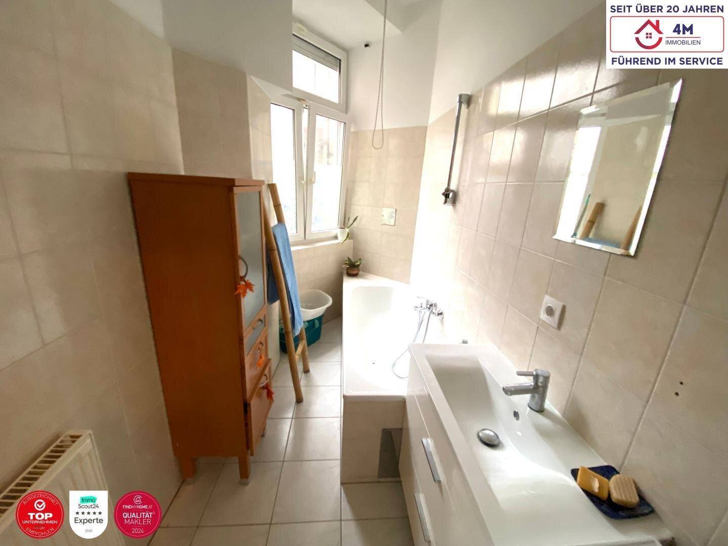 Helles Badezimmer mit Badewanne, Waschbecken und Fenster.