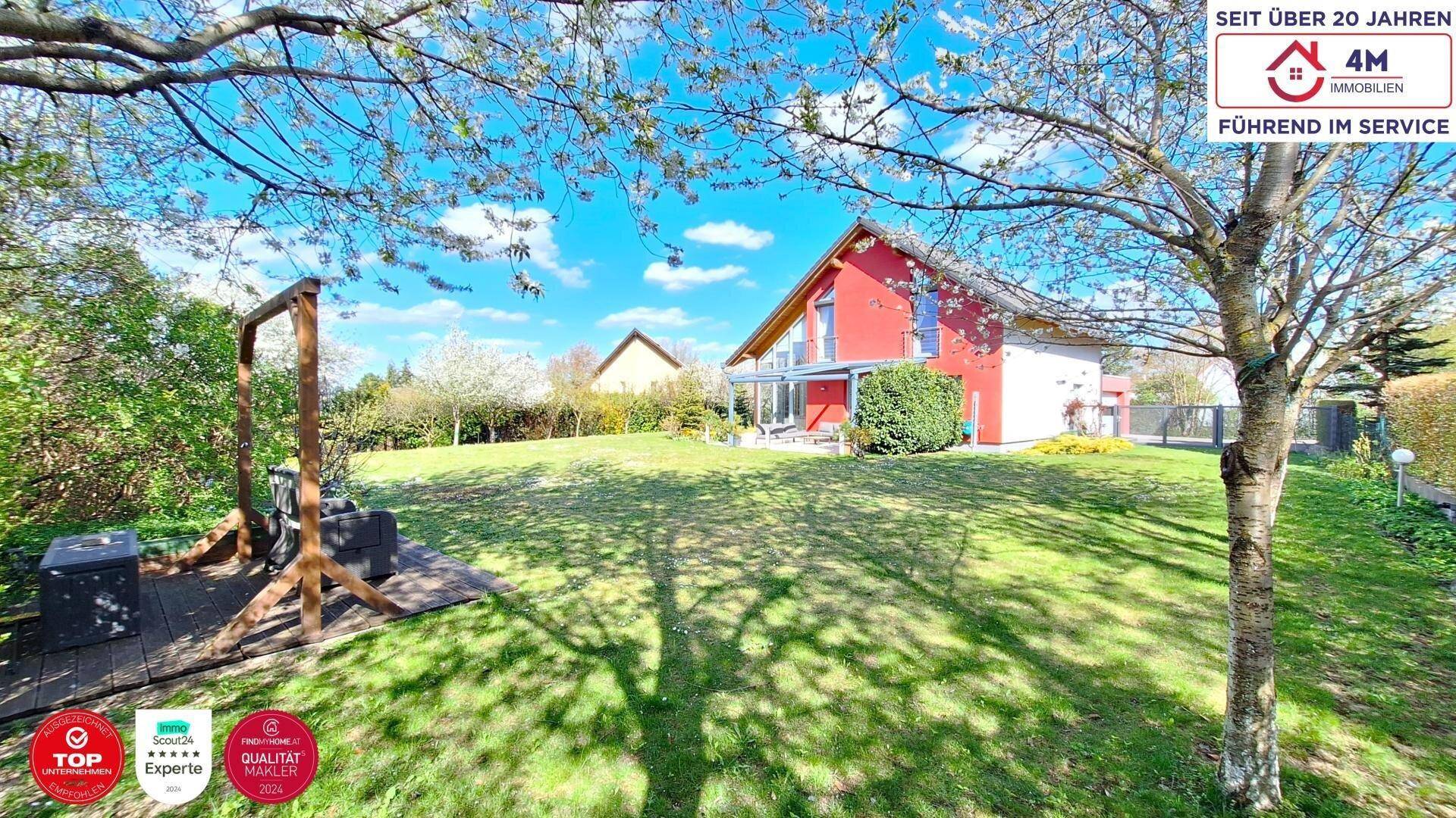 Großer, gepflegter Garten mit viel Rasenfläche, Bäumen und einem Spielbereich im Freien.