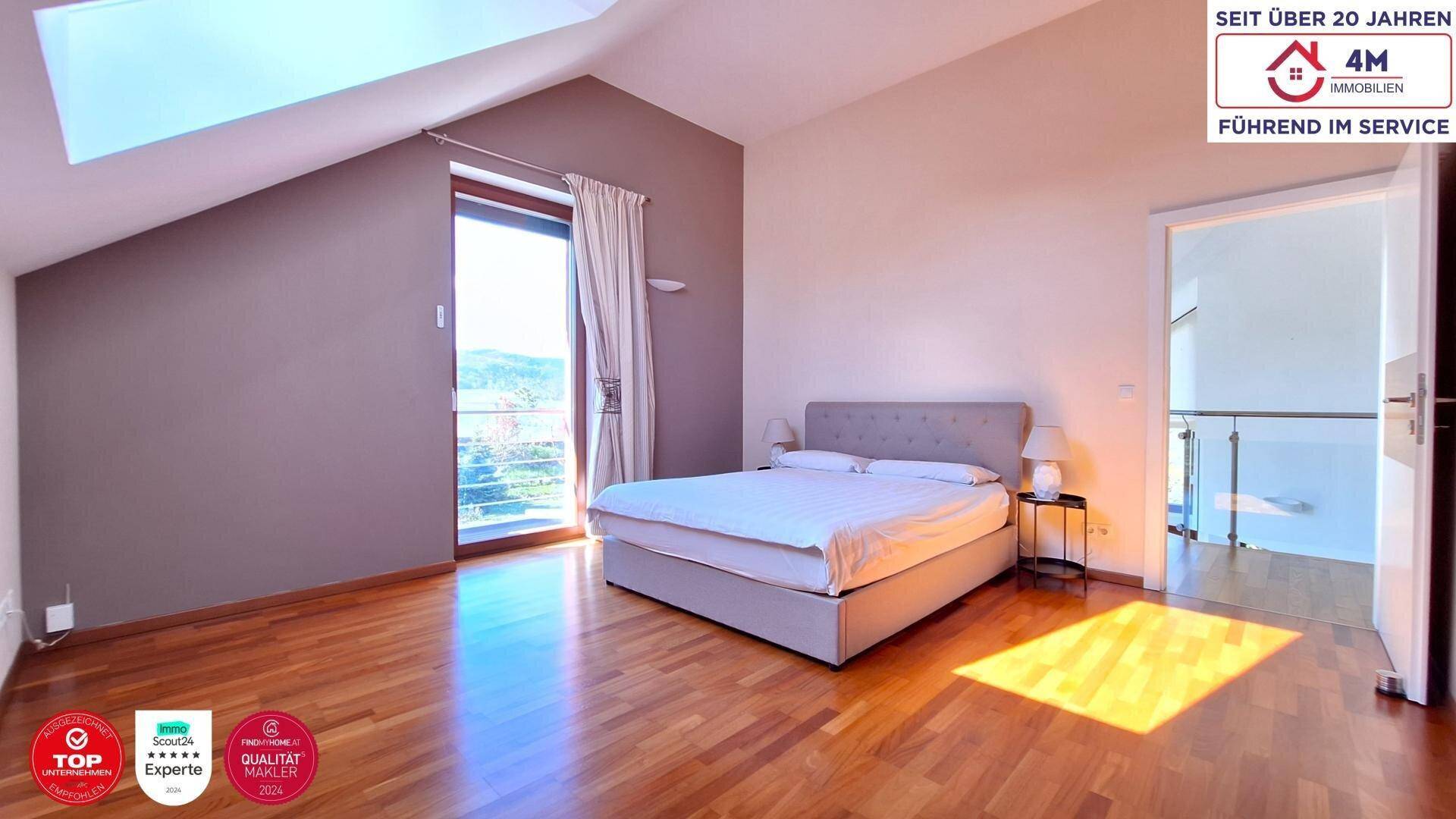 Gemütliches Schlafzimmer mit Holzboden, Dachschräge und Zugang zu einem Balkon mit schöner Aussicht.