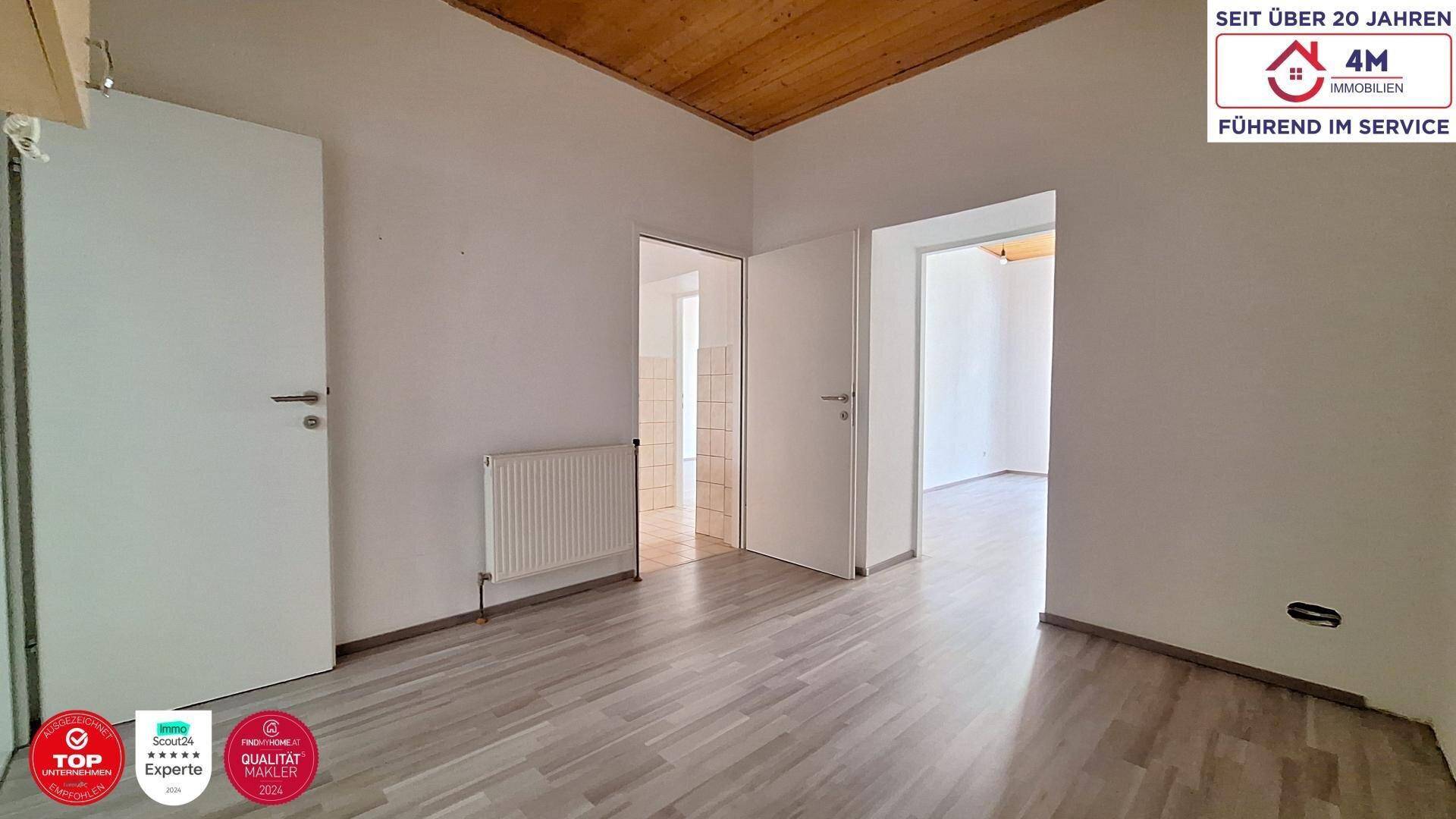 Flur mit Holzbalkendecke, Laminatboden und mehreren Türen, die zu angrenzenden Räumen führen.