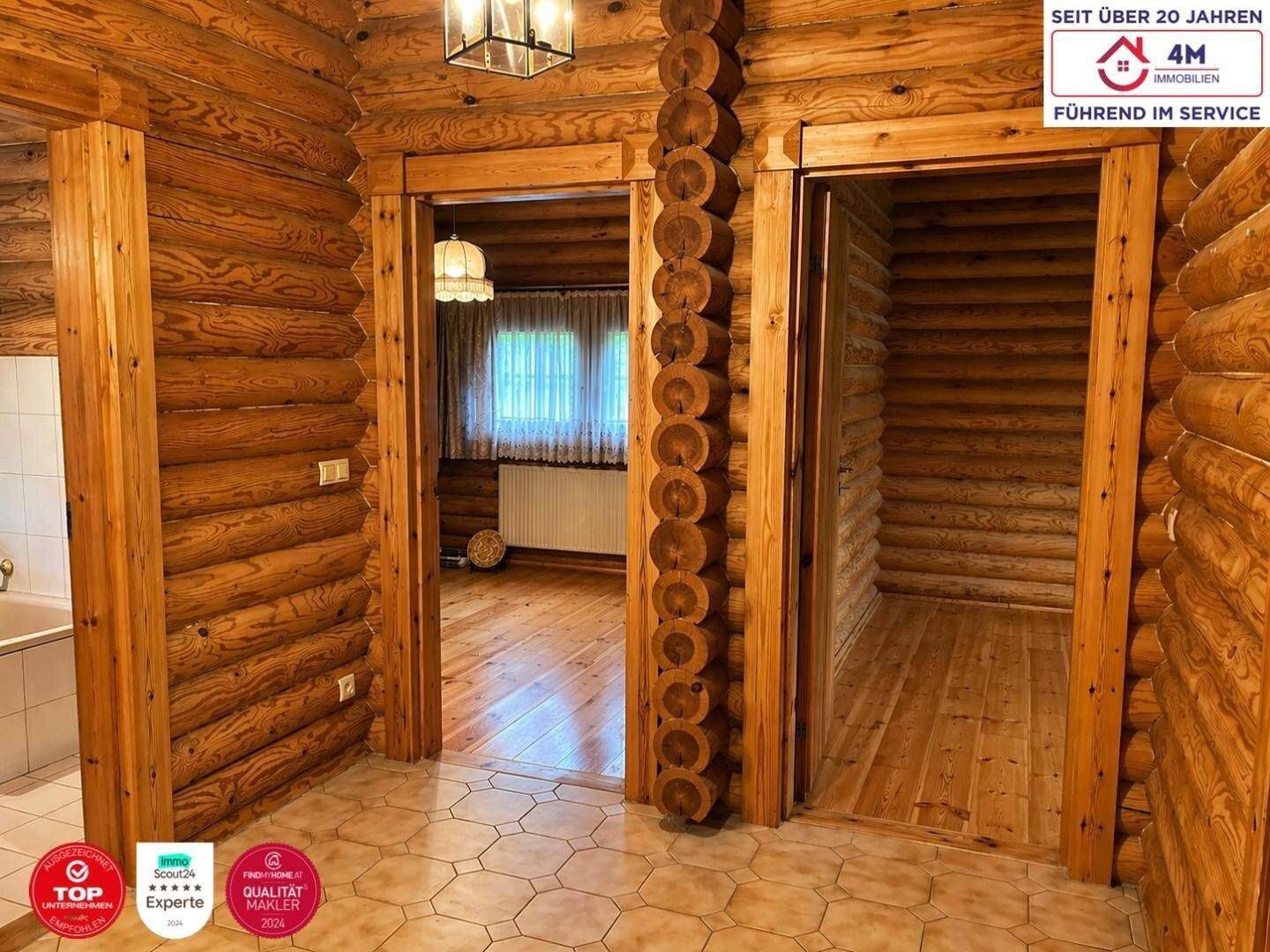 Rustikaler Flur im Blockhausstil mit Holzbalkenwänden und Türen zu weiteren Räumen.