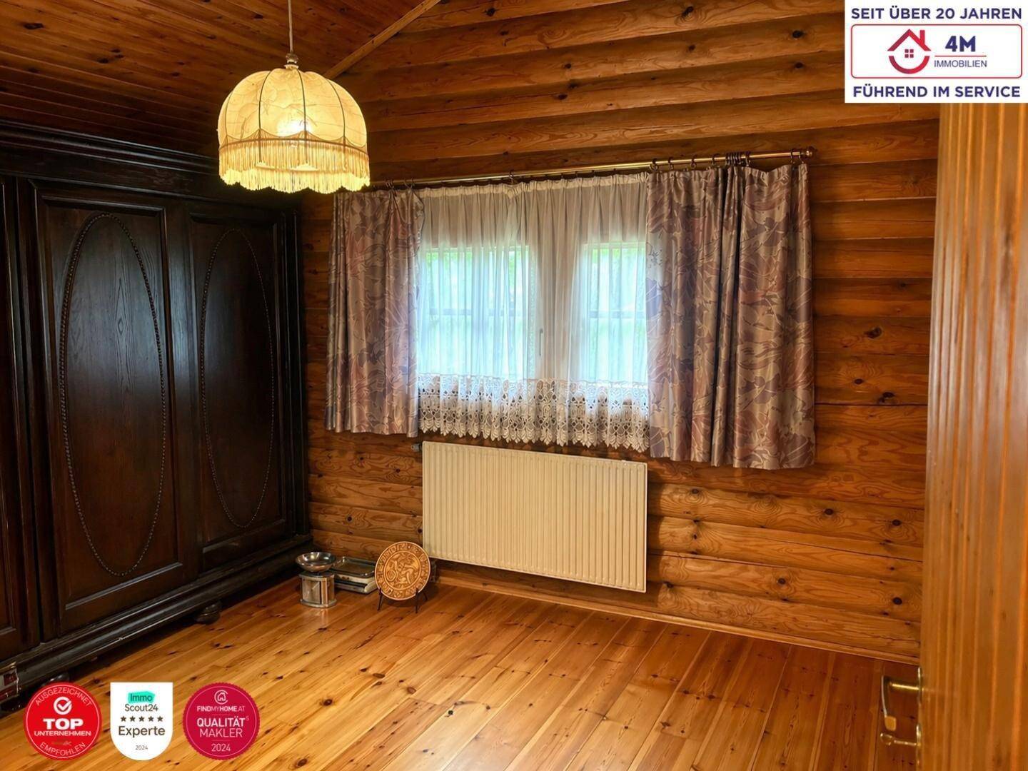 Schlafzimmer im Blockhausstil mit Holzwänden, großem Kleiderschrank, Fenster und Holzboden.