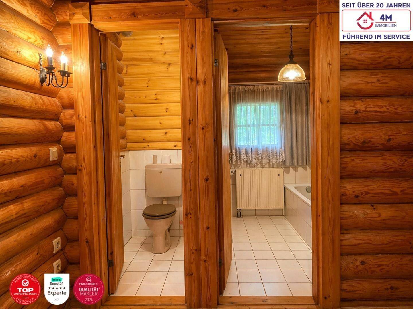 Kleiner Toilettenbereich im Blockhausstil mit Holzverkleidung und Fliesenboden, angrenzend an ein Badezimmer.