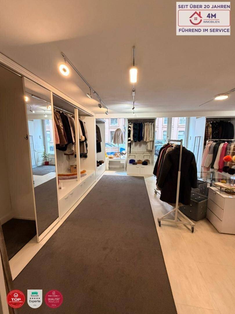 Langer Gang im Verkaufsraum mit Spiegeln, integrierten Regalen und Auslagen für Kleidung.