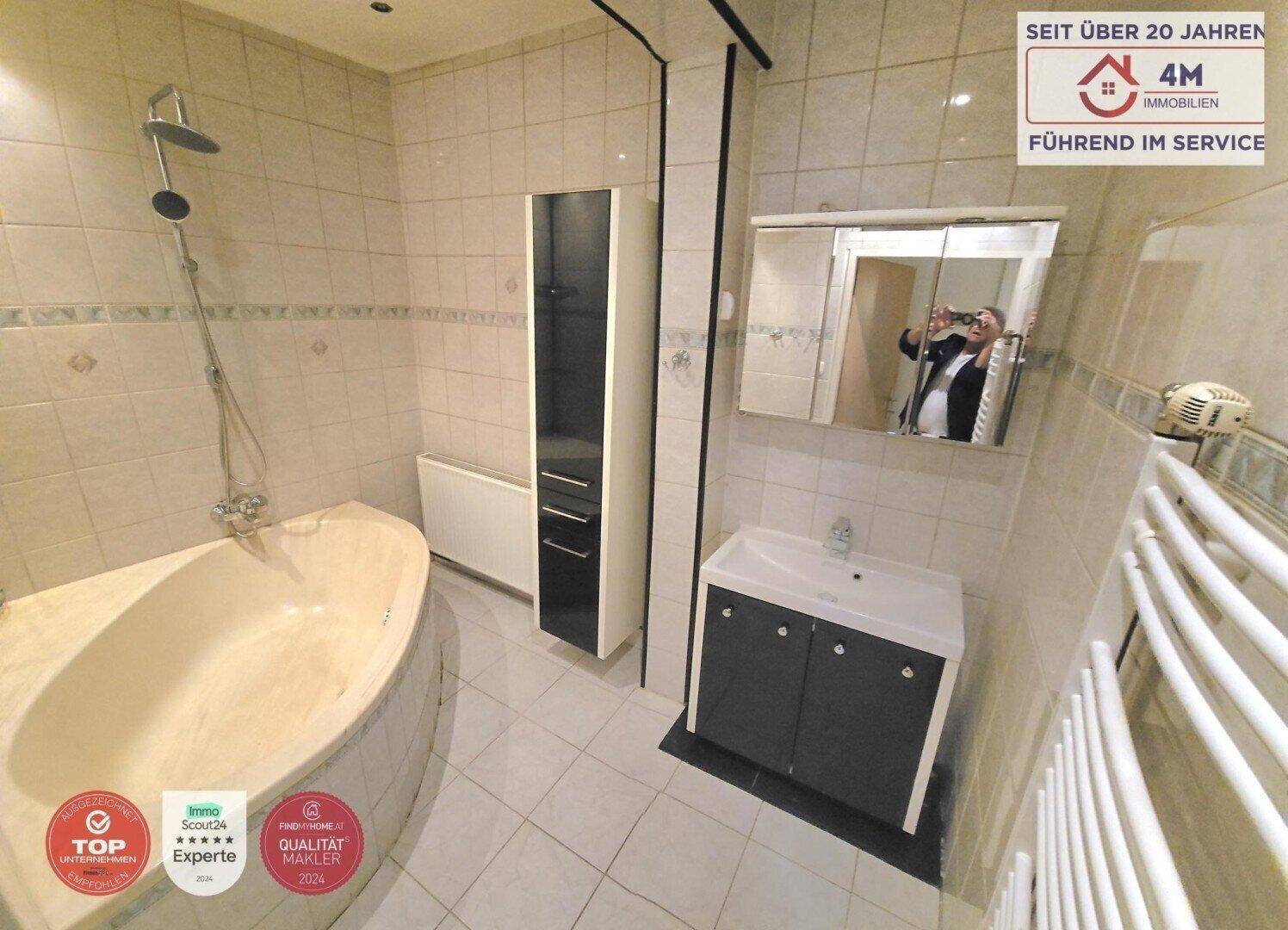 Badezimmer mit Eckbadewanne, Dusche, Waschbecken und Spiegelschrank.