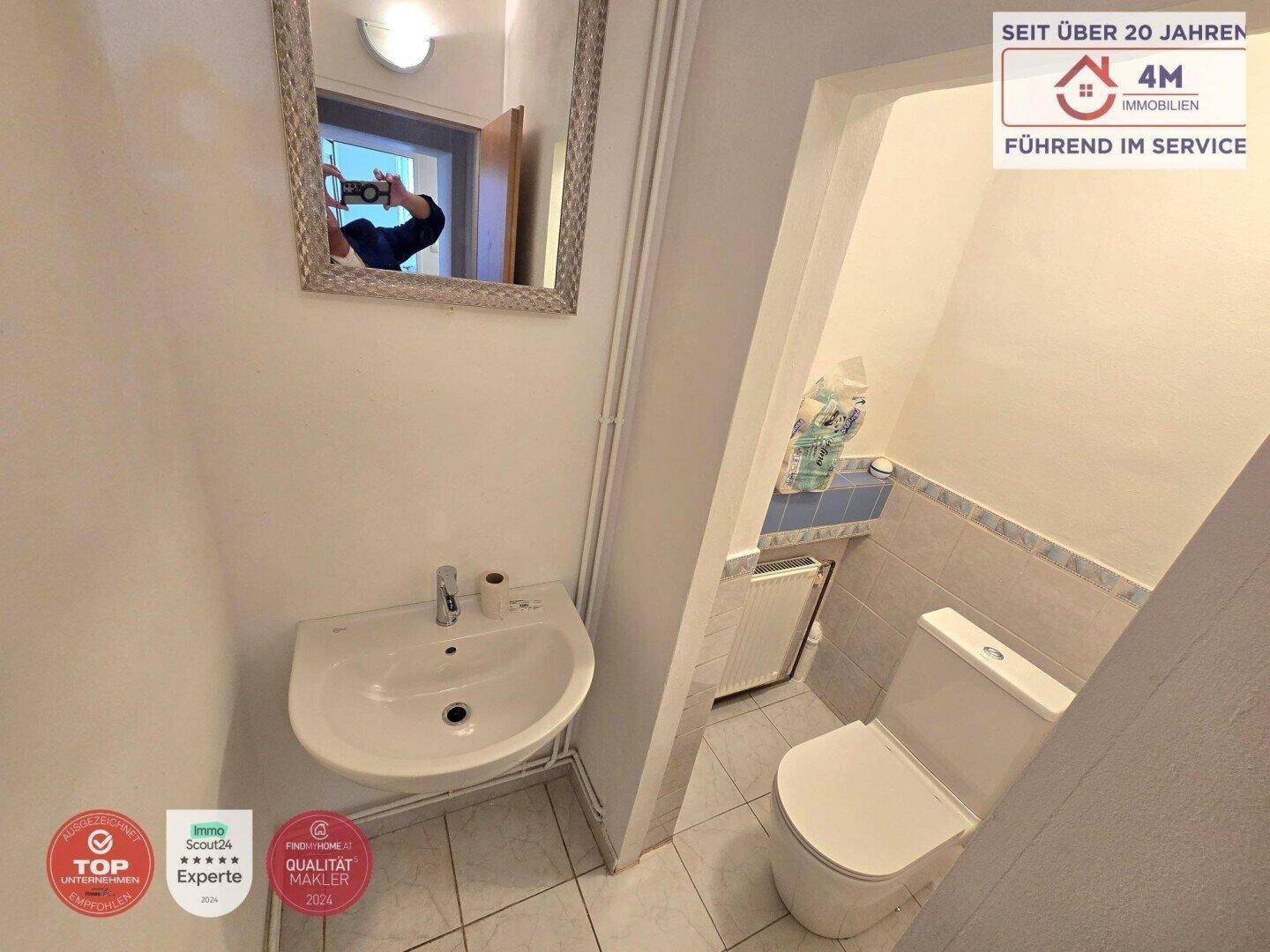 Kleines Gäste-WC mit Waschbecken, Toilette und Fliesenboden.