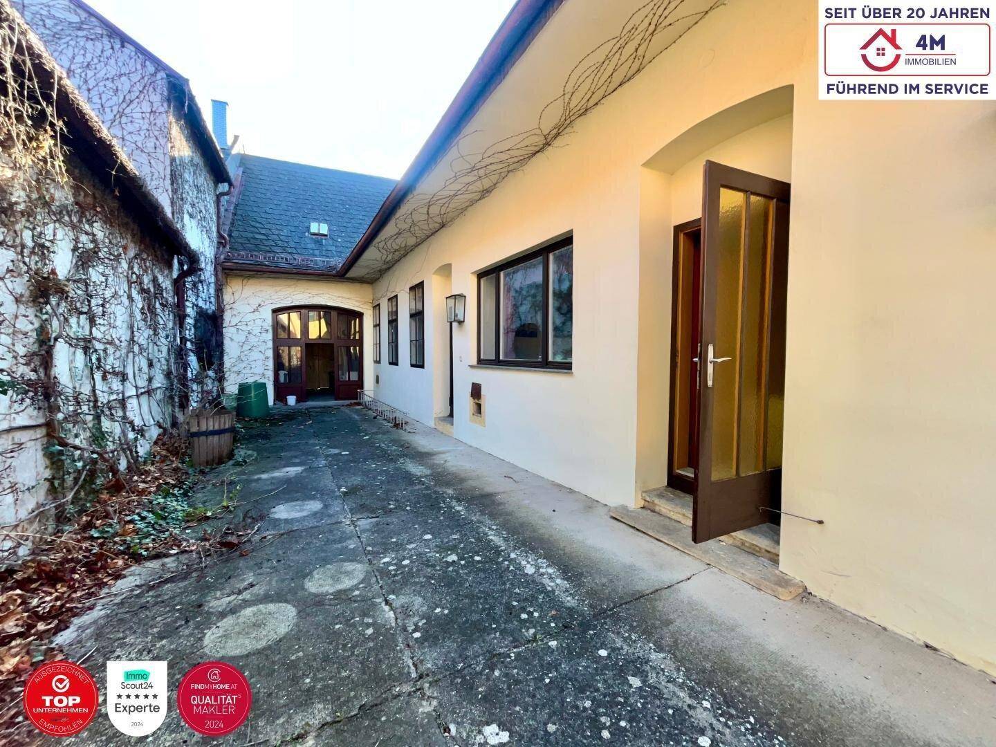 Außenbereich mit gepflastertem Hof, Efeu an der Wand und Zugang zum Gebäude, charmant und privat.