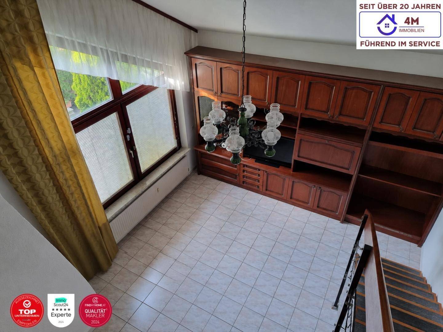 Blick von oben auf den Wohnbereich mit großem Holzschrank und Fliesenboden.