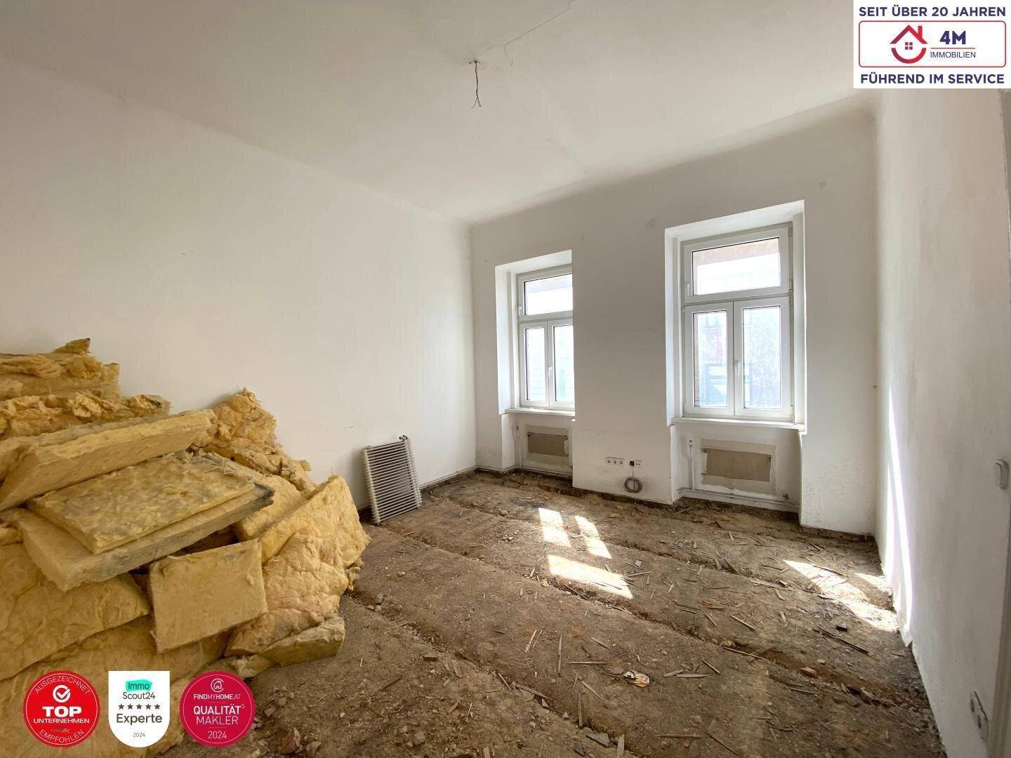 Raum im Rohzustand mit Dämmmaterial und Fenstern, bereit für den Ausbau.