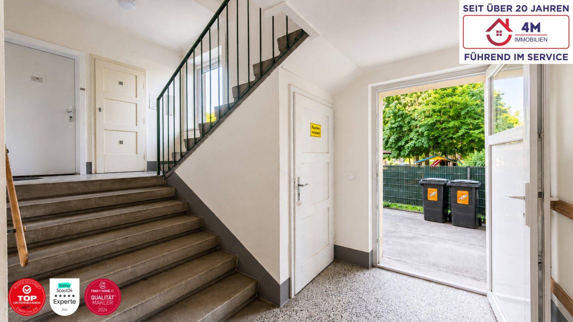 Treppenhaus im Eingangsbereich eines Mehrfamilienhauses mit Zugang zum Außenbereich.
