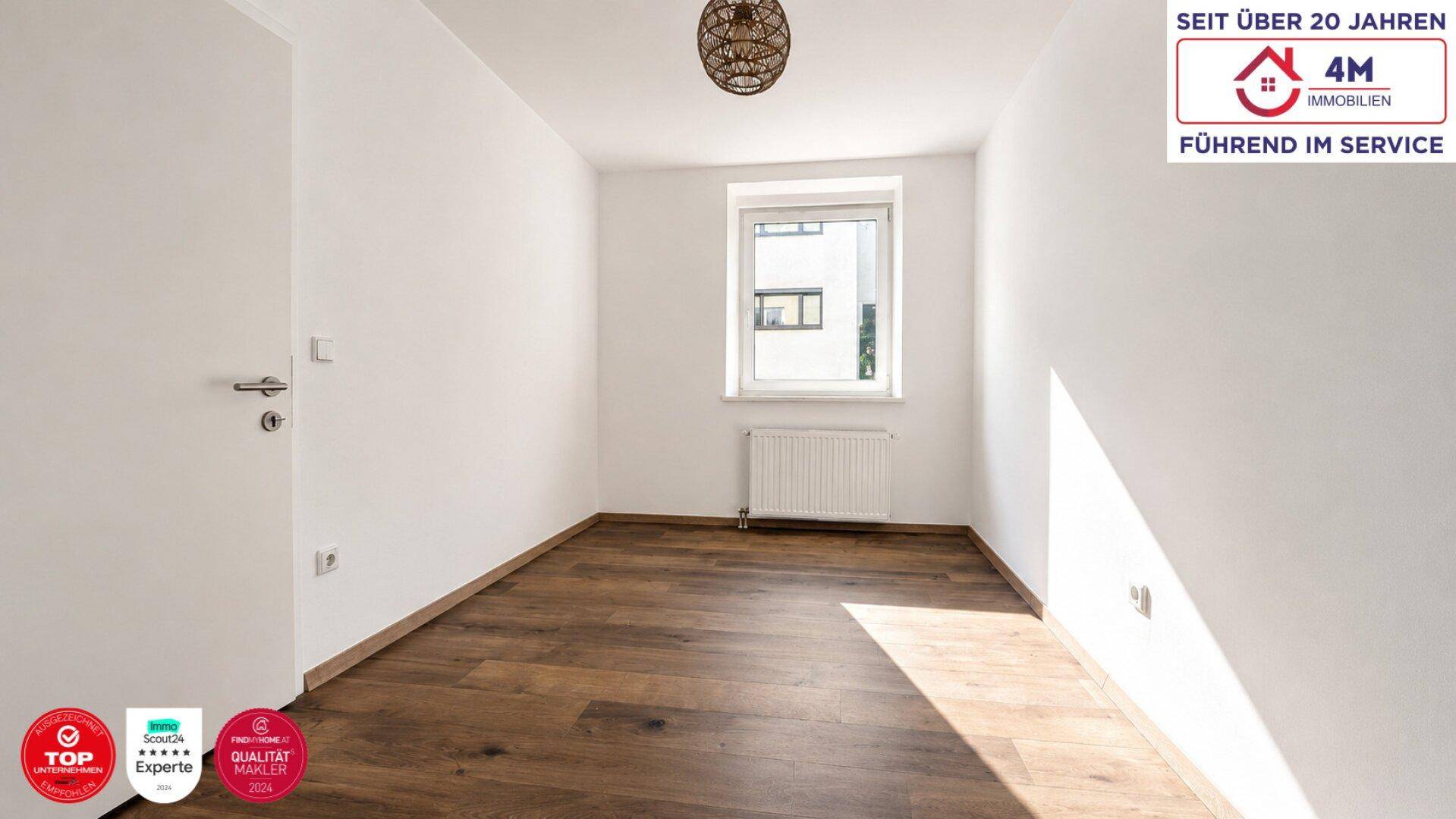 Helles, unmöbliertes Zimmer mit Holzboden, weißen Wänden und einem Fenster.