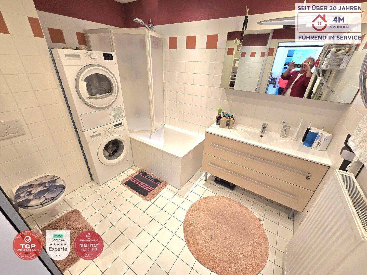 Funktionales Badezimmer mit Badewanne, Duschkabine, Waschbecken und Waschmaschine/Trockner.
