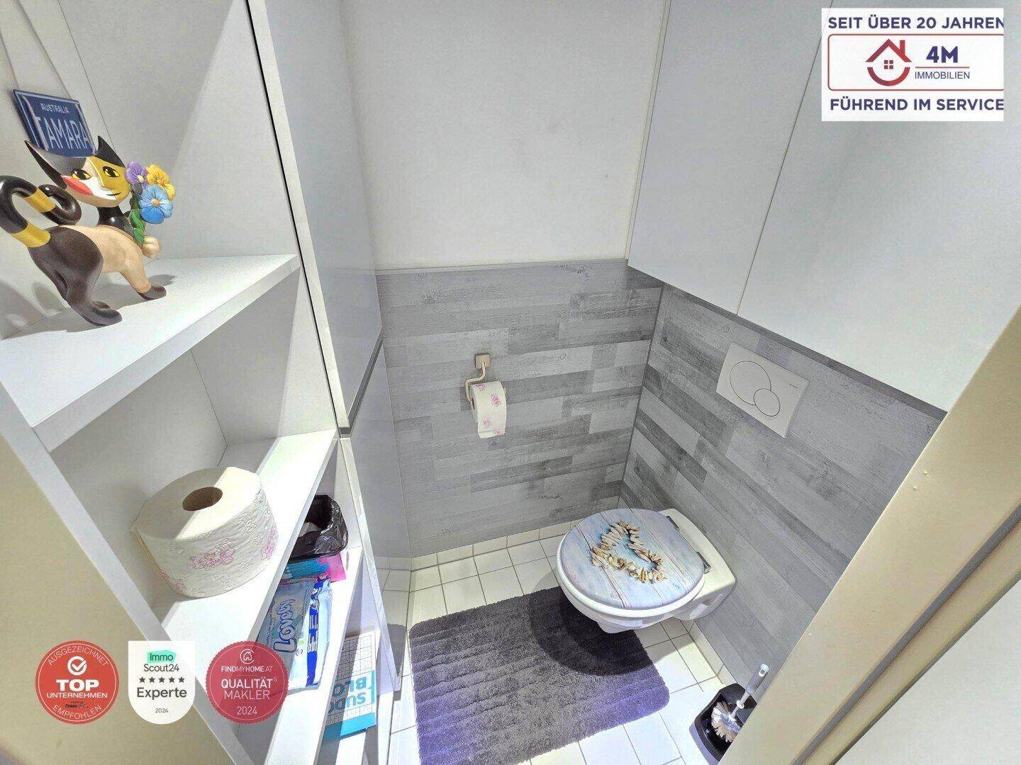 Kleines Gäste-WC mit Wand-WC, modernen Fliesen und praktischen Ablageregalen.
