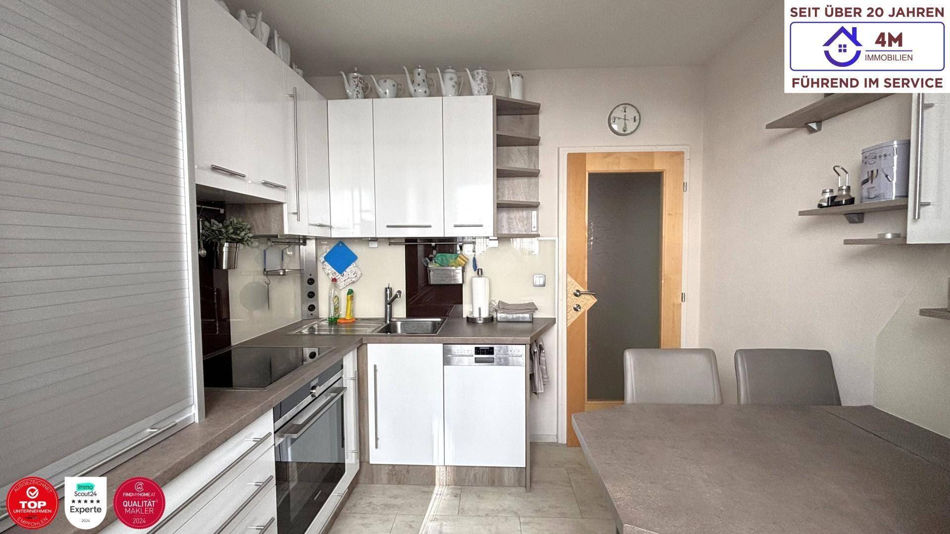 Funktionale Küche mit Spülmaschine, Spüle und kleinem Essbereich, gut beleuchtet.