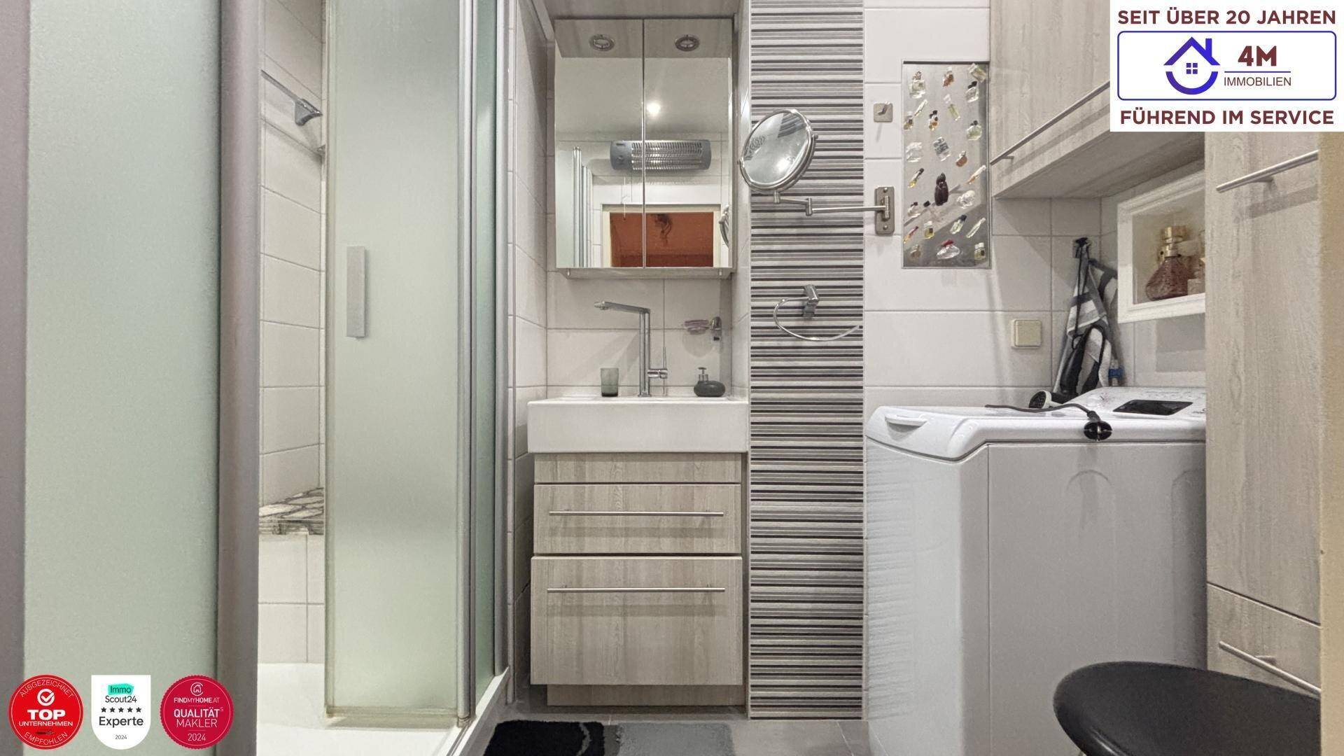 Modernes Badezimmer mit Duschkabine, Waschbecken und integrierter Waschmaschine.