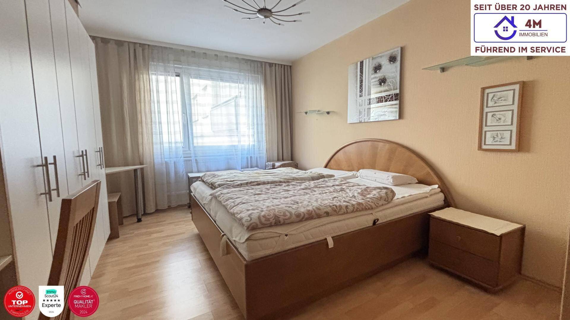 Schlafzimmer mit Doppelbett, hellem Laminatboden und großem Fenster für viel Tageslicht.